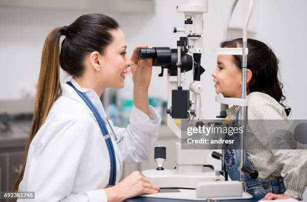 girl getting an eye exam at the optician - eye test equipment stock pictures, royalty-free photos & images