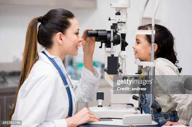 girl getting an eye exam at the optician - eye test equipment imagens e fotografias de stock