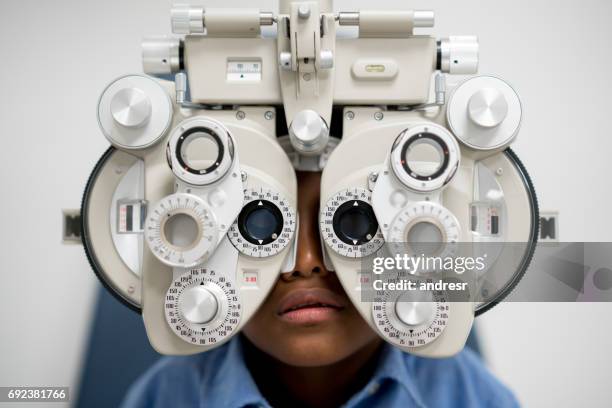 boy getting an eye exam at the optician - kids eye test stock pictures, royalty-free photos & images