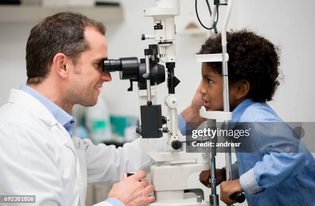 boy getting an eye exam at the optician - kids eye test stock pictures, royalty-free photos & images