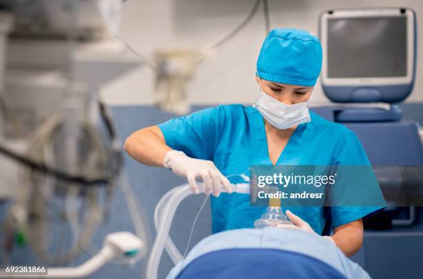 enfermera pone la máscara de oxígeno al paciente durante la cirugía - medical oxygen equipment fotografías e imágenes de stock