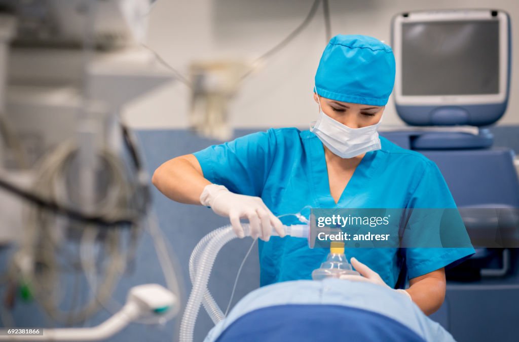 Nurse putting oxygen mask to patient during surgery