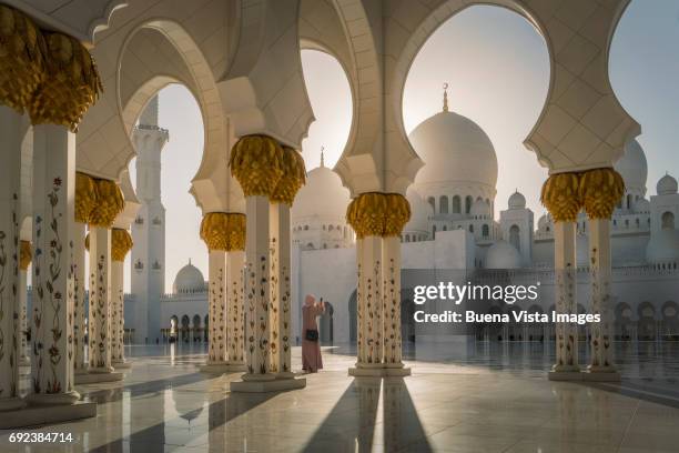 woman with abaya taking pictures in a mosque - masjid stockfoto's en -beelden