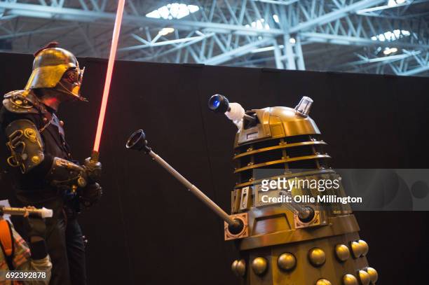 Cosplayer in character as a Steampunk version of Darth Vader from Star Wars acts out a ballte with a Dalek from Dr Who at The Birmingham Film and...