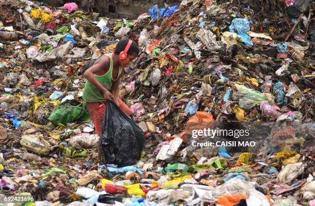 An Indian boy wearing headphones searches for recyclable items at a garbage dump in Dimapur, in the northeastern state of Nagaland, on June 5 on...