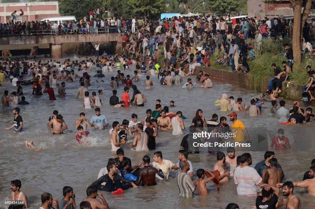 Pakistani people taking bath in the canal water to beat the...