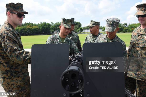 Philippine Marines and their US counterpart look at an M134D Gatling-style machine gun during a handover ceremony of weapons from the US military, at...