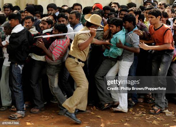 Policeman uses a bamboo stick to move men back into a line for tickets for the India versus England Group B cricket World Cup match at the M...