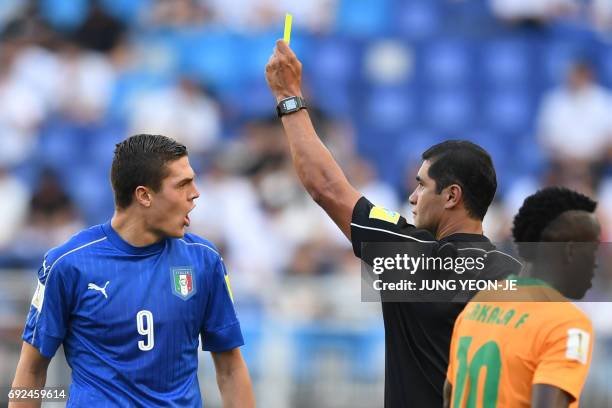 The referee gives a yellow card to Italy's forward Andrea Favilli during the U-20 World Cup quarter-final football match between Italy and Zambia in...