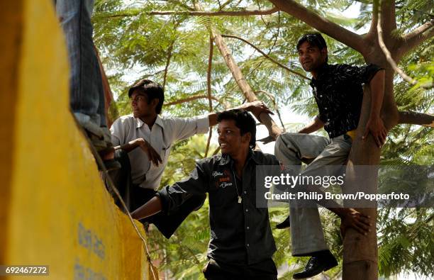 Men climb a tree and a wall so that they can see the Indian team training before Sunday's ICC Cricket World Cup group B clash against the West Indies...