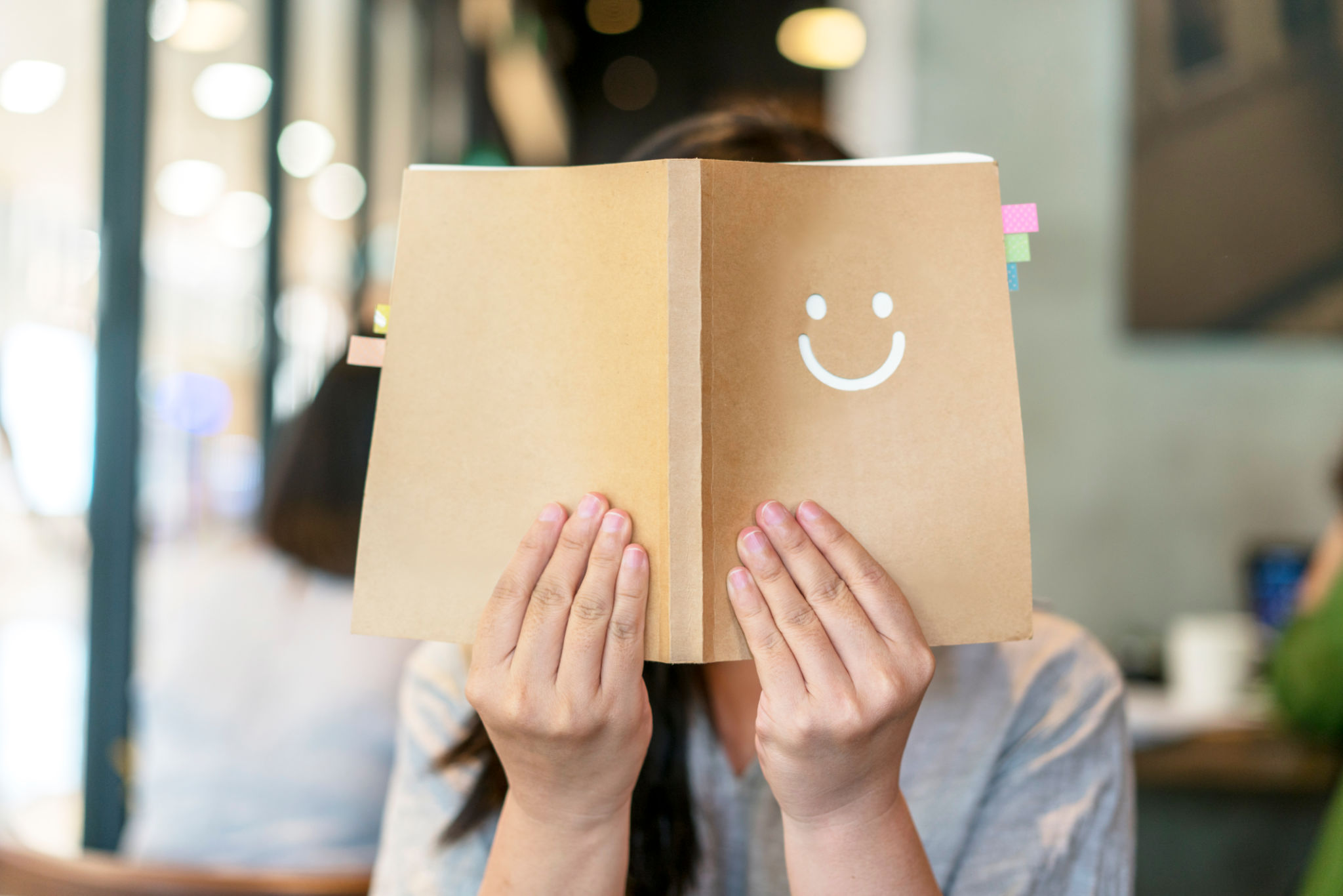 girl holding book covering face girl holding book covering face