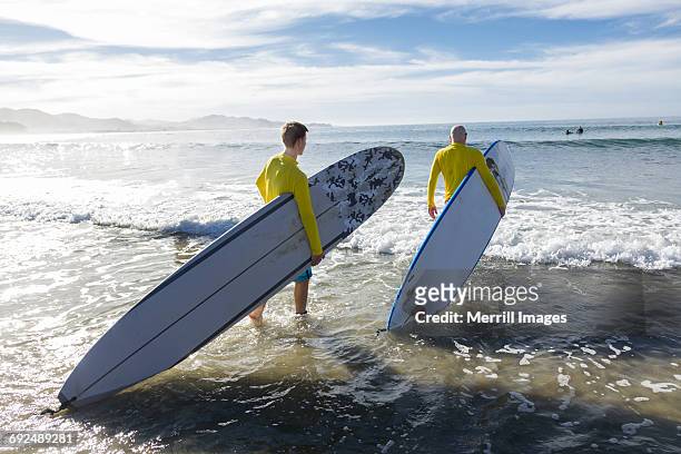 teenage boy and father surfing. - todos santos mexico fotografías e imágenes de stock