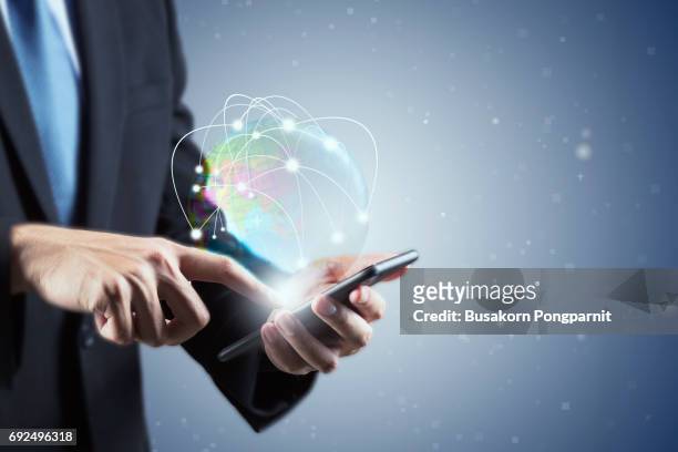 double exposure of  businessman hand using smartphone with world hologram in technology and social concept holding smartphone with digital graphic - global press conference stock-fotos und bilder