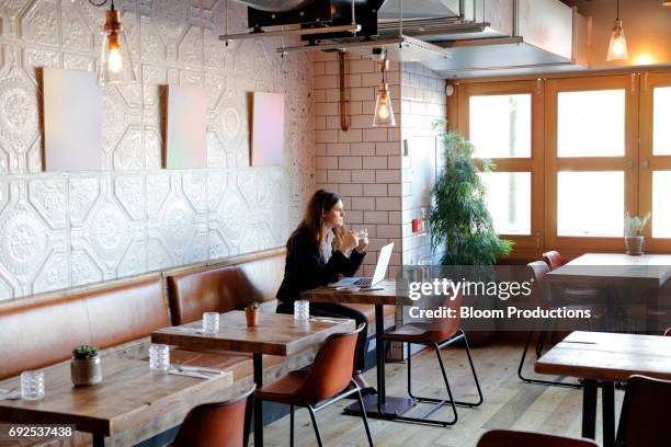 business women in a restaurant / cafe looking out of the window - cafe window stock pictures, royalty-free photos & images