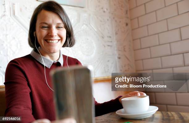 young woman smiling using a smart phone - in ear headphones stock pictures, royalty-free photos & images