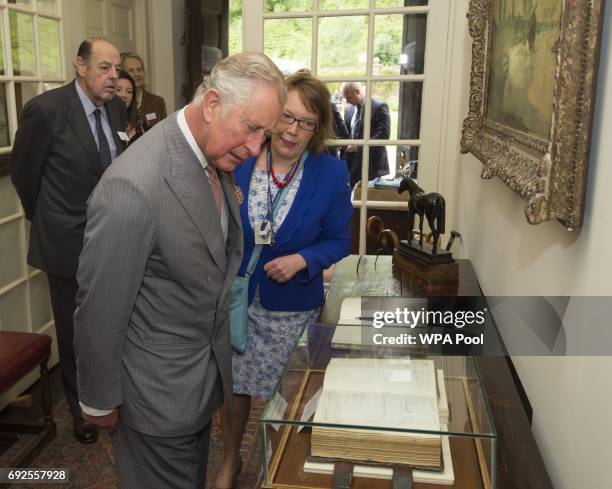 Prince Charles, Prince of Wales, President of The National Trust views the visitors book with the signature of his Grandmother Queen Elizabeth during...
