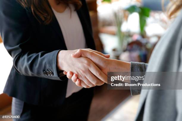 two business women shaking hands - deal england stock-fotos und bilder