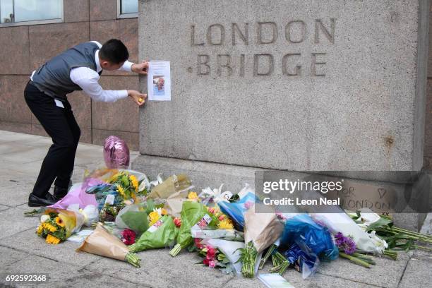 Man re-attaches a missing person poster above floral tributes on London Bridge, after it was reopened following the June 3rd terror attack on June 5,...
