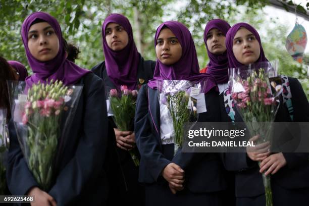 Pupils from Eden Girls' School in Walthamstow holds flowers at Potters Fields Park in London on June 5 during a vigil to commemorate the victims of...