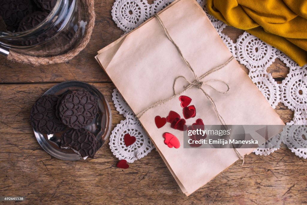 Wrapped empty old paper and cocoa cookies on wooden table