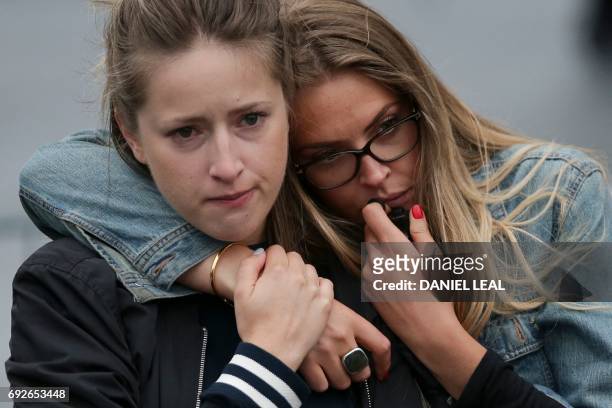 Two women react as they pause at the mound of flowers outside City Hall in London on June 5, 2017 in tribute to the victims of the terror attack on...