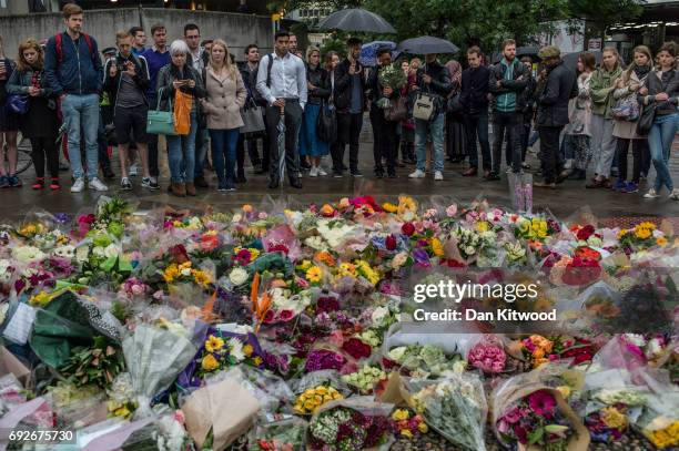 Members of the public gather near flowers on the South side of London Bridge, close to Borough Market in London in tribute to the victims of the June...