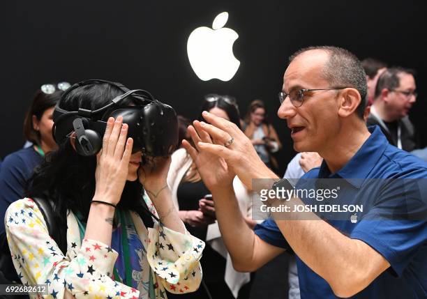 An Apple employee helps a member of the media try on an HTC Vive while testing the virtual reality capabilities of the new iMac during Apple's...