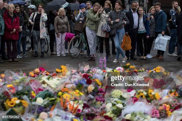 Members of the public gather near flowers on the South side of London Bridge, close to Borough Market in London in tribute to the victims of the June...