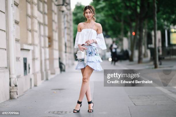 Bianca Derhy, fashion blogger Bibi Goes Chic, wears a Revolve off shoulder lace top, a Shein blue ruffled flower print skirt, a Furla bag, and black...