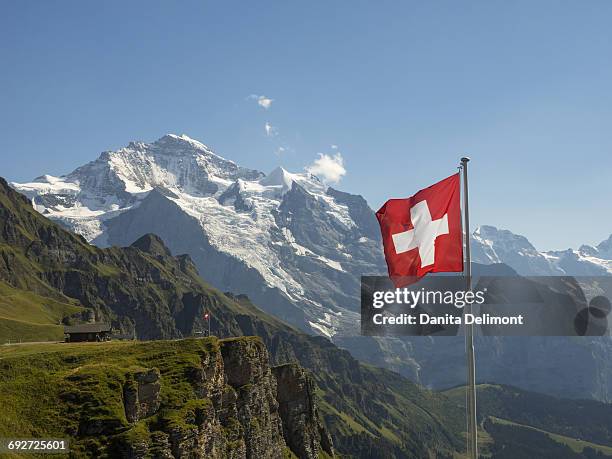 swiss flag and jungfrau mountain, bern canton, switzerland - mannlichen foto e immagini stock