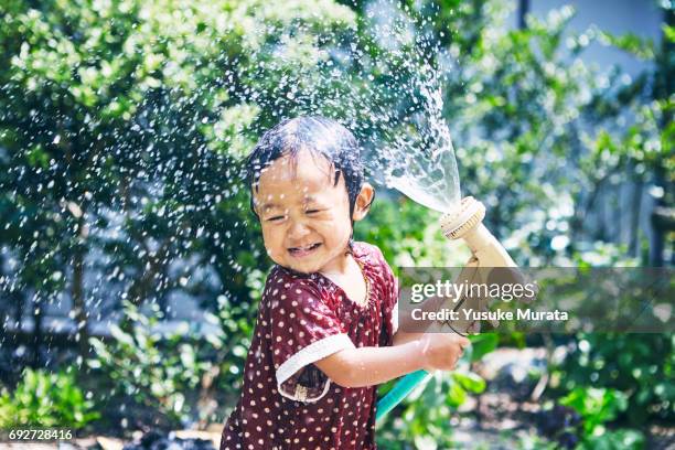 little girl spraying water hose - 子供　日本人　笑顔 ストックフォトと画像