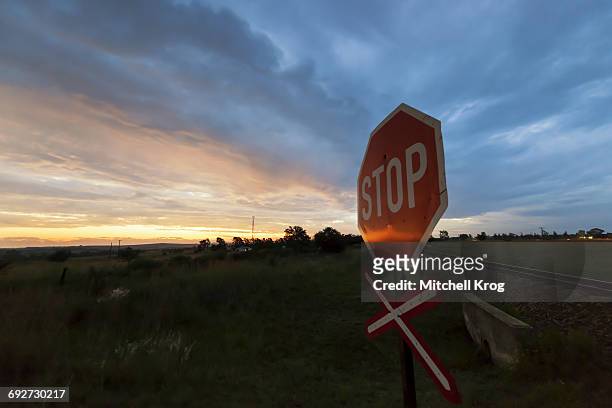 railway crossing warning signal with stop sign at sunset near the town of magaliesburg, gauteng province, south africa - gauteng province stockfoto's en -beelden