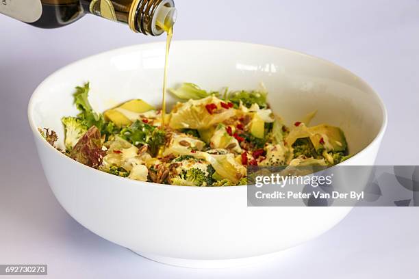 a bowl containing green salad with avocado and nuts drizzled with olive oil, western cape province, south africa - avocado oil stock pictures, royalty-free photos & images