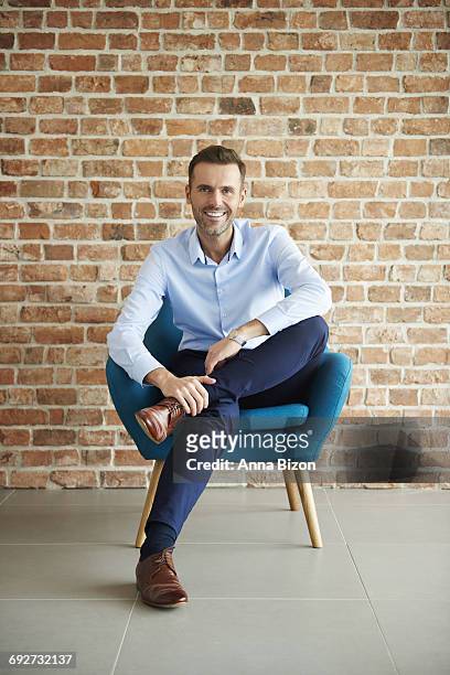 portrait of man in a blue armchair. debica, poland - portrait man suit smiling light background stock pictures, royalty-free photos & images