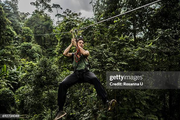 man on zip wire in forest, ban nongluang, champassak province, paksong, laos - zip line stock pictures, royalty-free photos & images