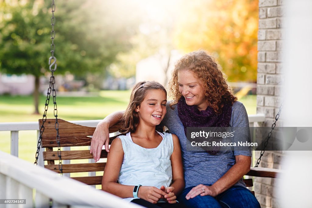 Aunt and niece sitting on porch swing, smiling