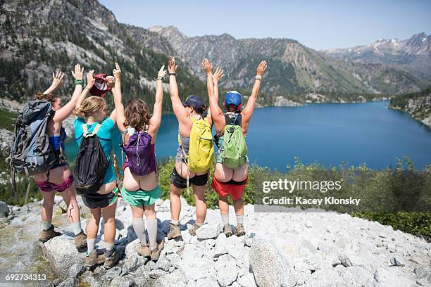 five young women, standing on rock beside lake, arms raised, rear view, the enchantments, alpine lakes wilderness, washington, usa - public liability stock-fotos und bilder