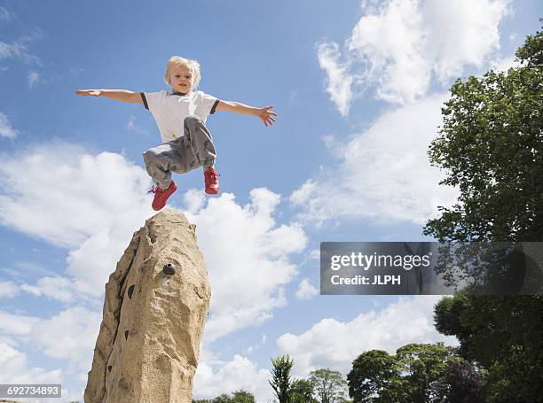 boy jumping from rock - boy rock climbing stock-fotos und bilder