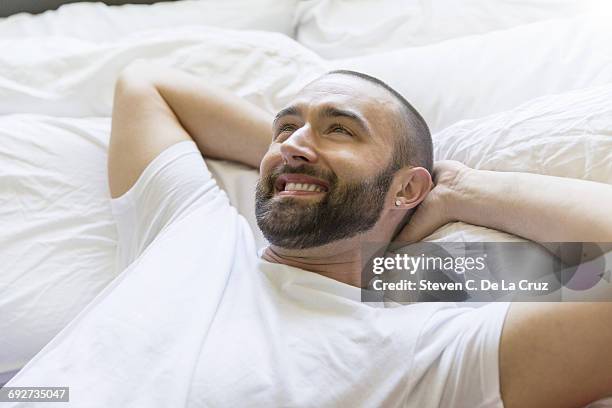 happy mid adult man lying in bed - bed side view stock pictures, royalty-free photos & images