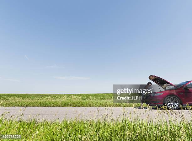 woman looking under hood of broken down car - bad luck stock pictures, royalty-free photos & images