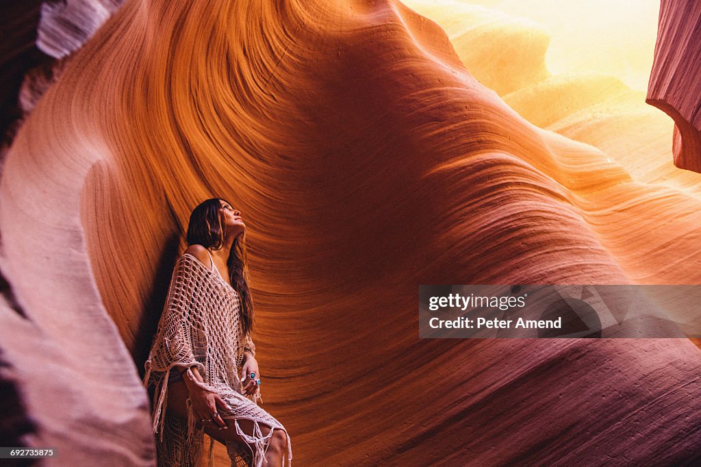 Woman looking up at sunlight in cave, Antelope Canyon, Page, Arizona, USA