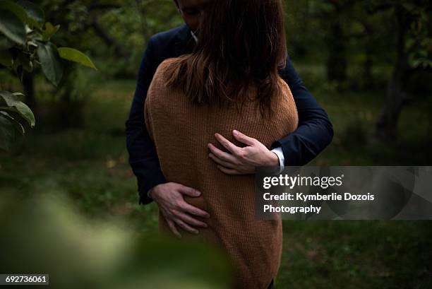 mid section of romantic couple hugging in orchard at dusk - heteroseksueel koppel stockfoto's en -beelden