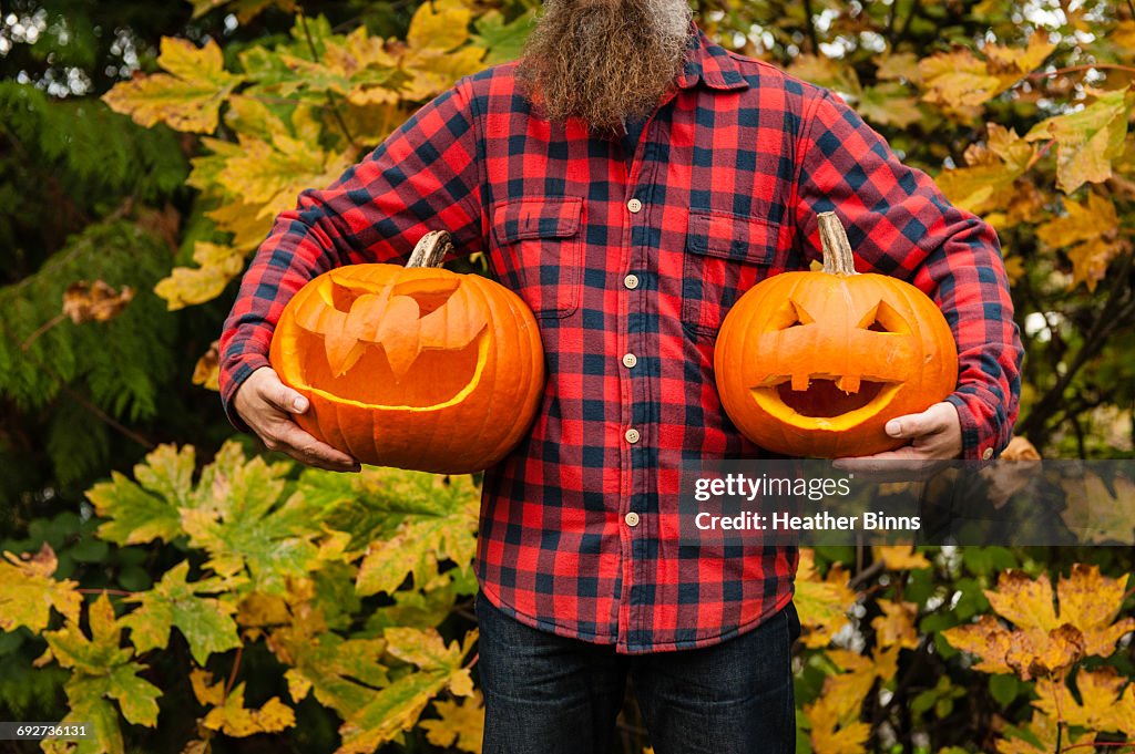 Mature man holding carved pumpkins