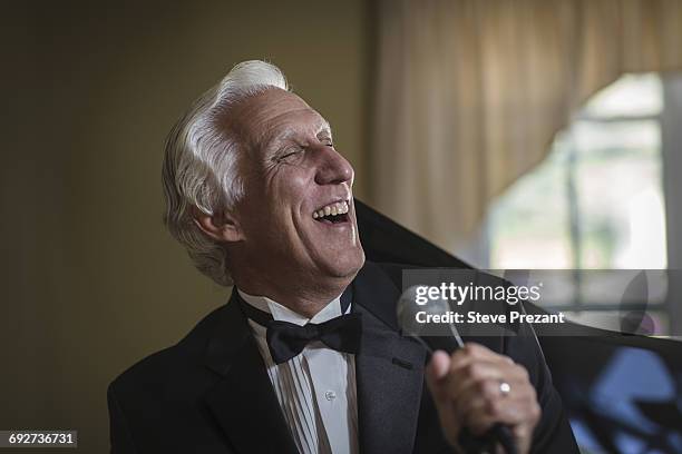 senior man in bow tie singing into microphone - performer bildbanksfoton och bilder