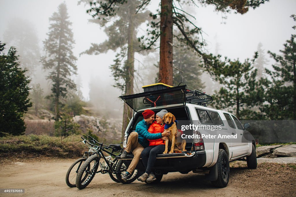 Couple and dog sitting on tailgate of jeep wagon, Sequoia National Park, California, USA