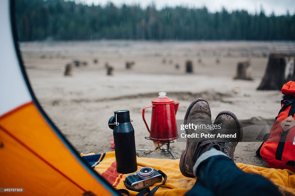 Young man sitting in tent on beach, Huntington Lake, California, USA