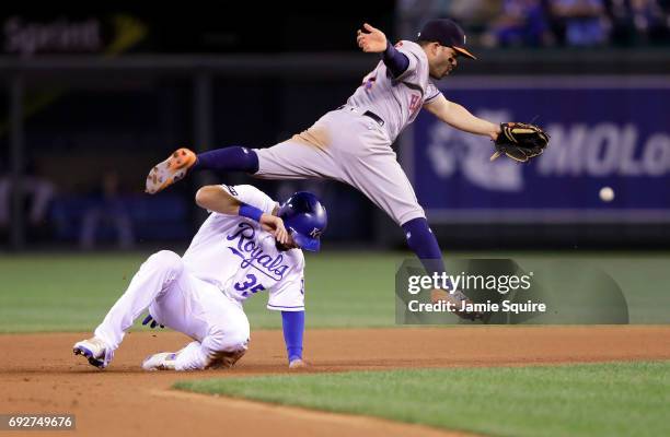 Jose Altuve of the Houston Astros leaps over Eric Hosmer of the Kansas City Royals on an errant throw during the 6th inning of the game at Kauffman...