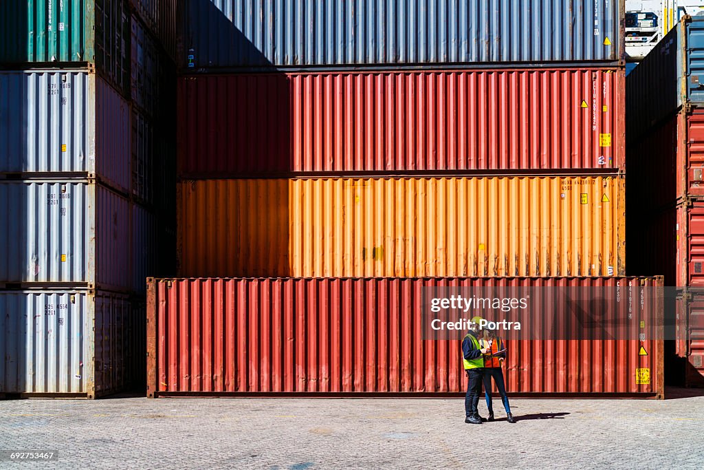 Workers having discussion against cargo containers
