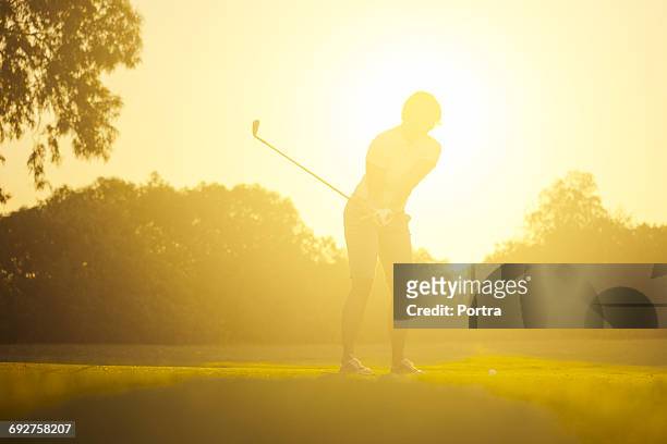 golfer swinging golf club on sunny day - natural shot female stock-fotos und bilder