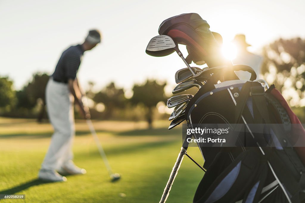 Close-up of golf bag with people in background